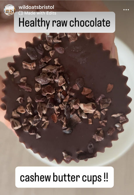 A close-up of a homemade raw chocolate cup topped with crunchy cacao nibs, labelled “Healthy raw chocolate” and “cashew butter cups.”