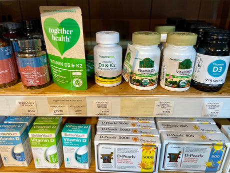 Vitamin D and D3 with K2 supplements on shelves at Wild Oats Bristol, including capsules and oral sprays from several brands.