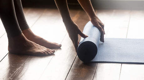 Woman folding her yoga mat up after yoga class in Bristol.