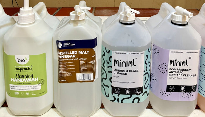 Row of eco-friendly cleaning products with various labels on a white surface.